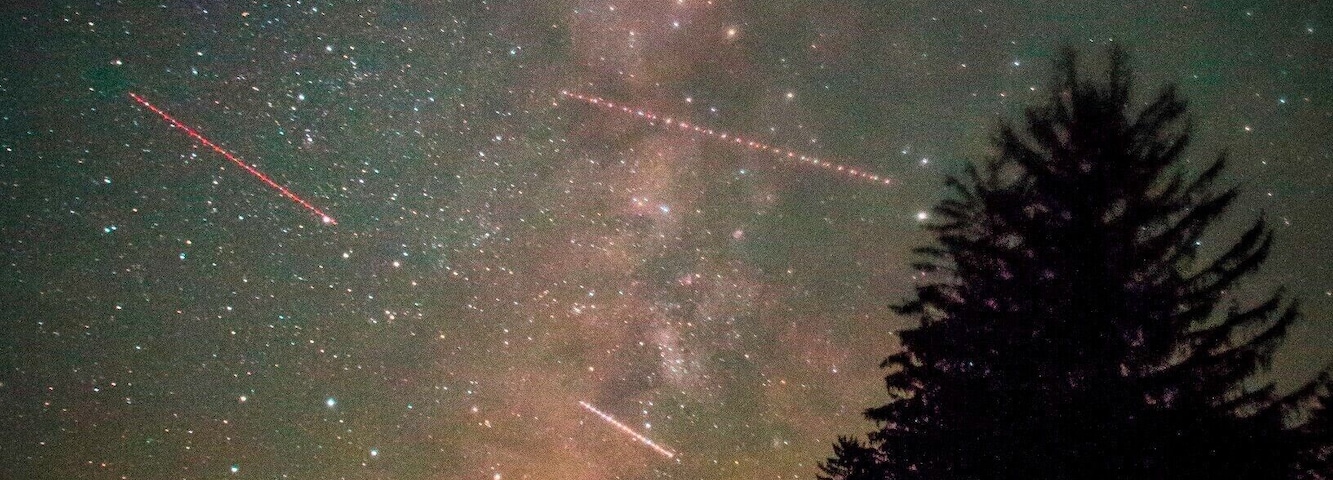 Un observatorio abovedado bajo un cielo estrellado con la Vía Láctea visible y estrellas fugaces.