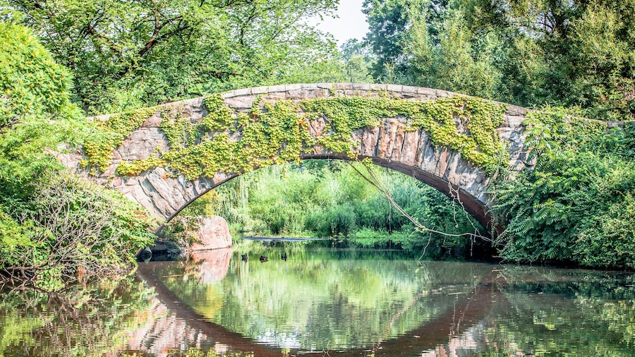 Beautiful Gapstow bridge reflecting in water in Central Park, New York City during summer sunny day