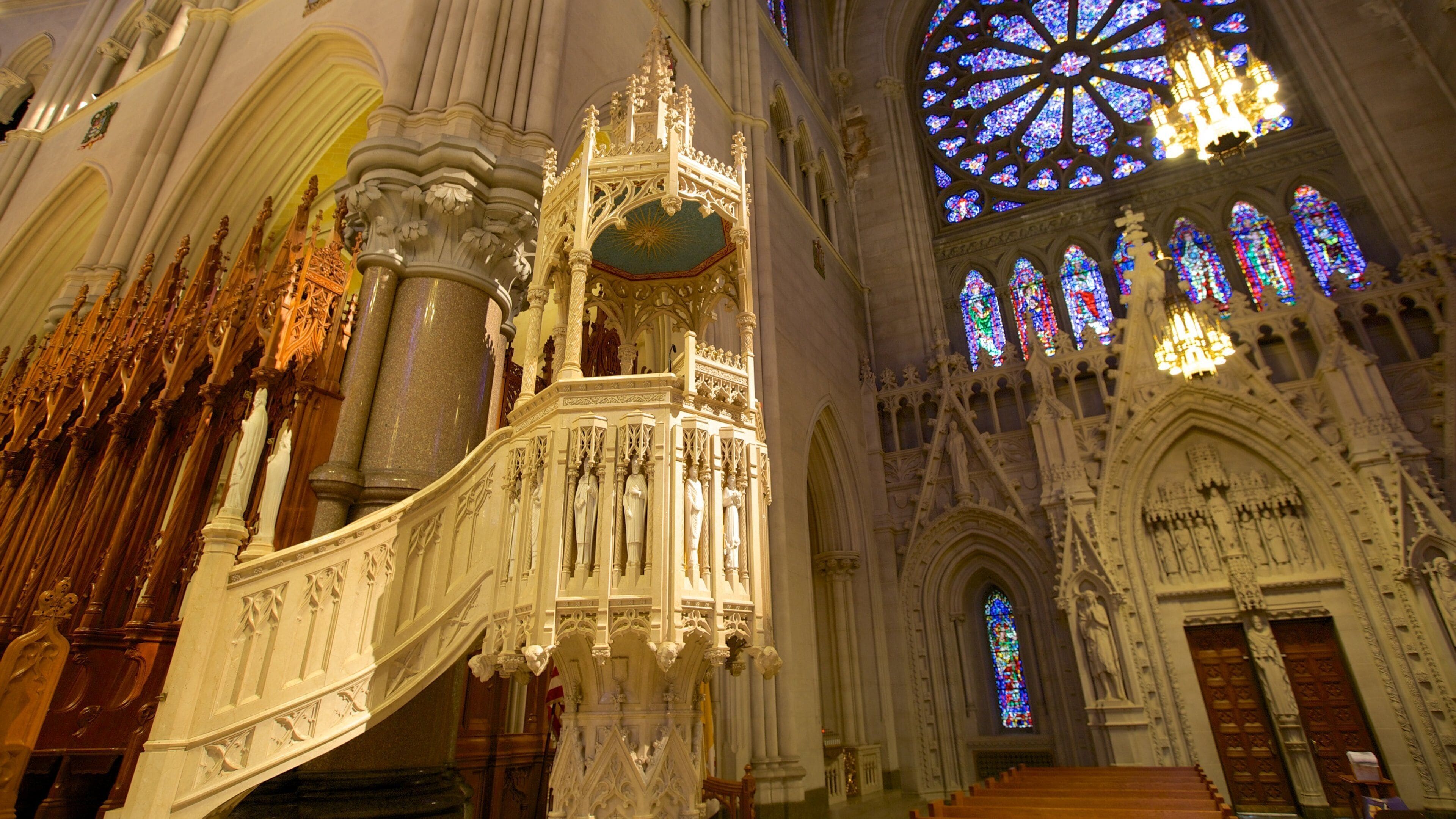 L’intérieur d’une cathédrale, avec son architecture richement décorée, ses vitraux et une grande rosace.