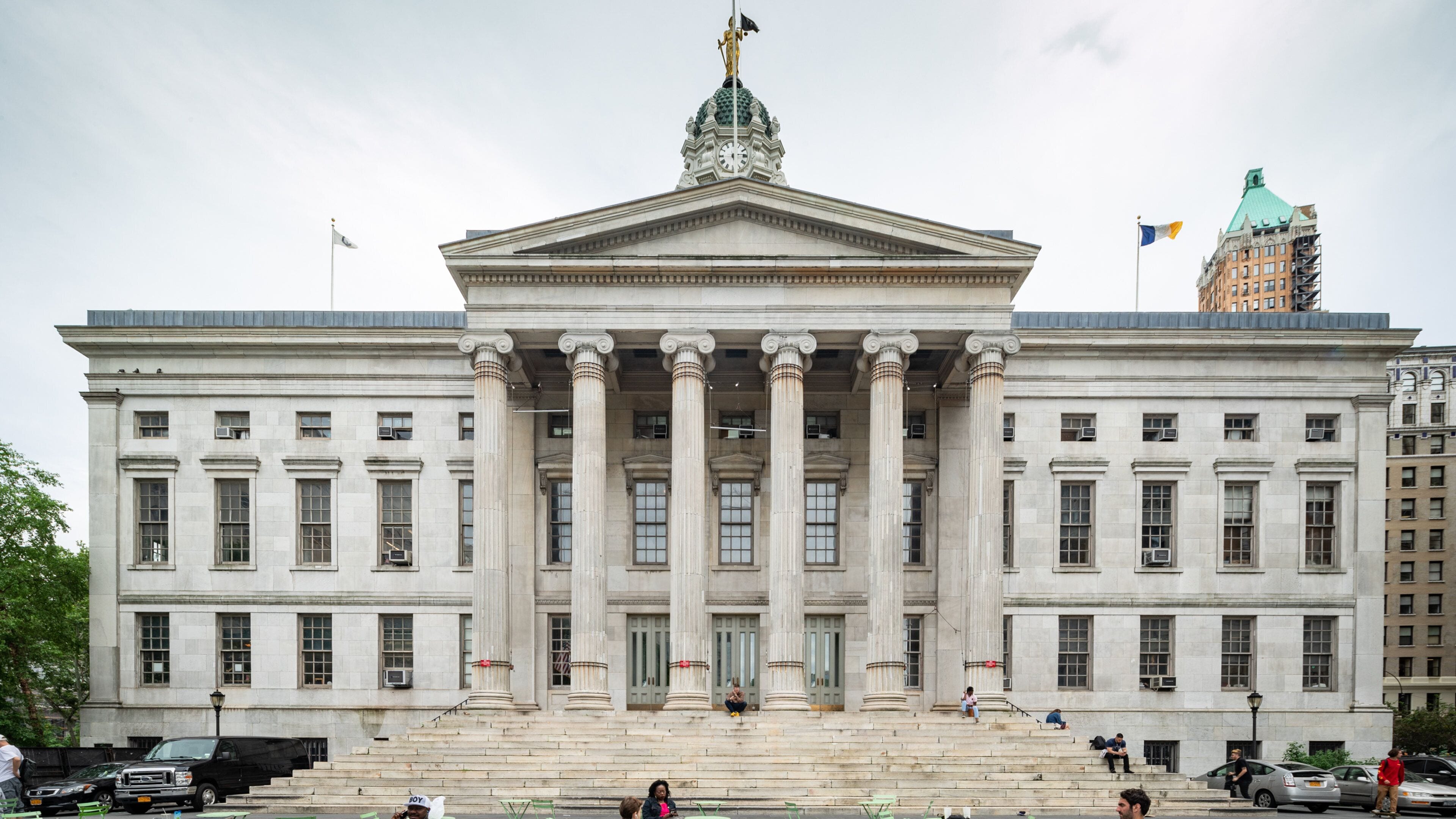 A large neoclassical building with a prominent central entrance, flanked by columns, and a clock tower.