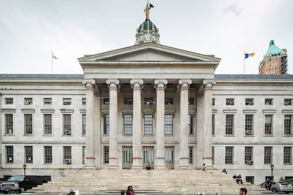 A large neoclassical building with a prominent central entrance, flanked by columns, and a clock tower.