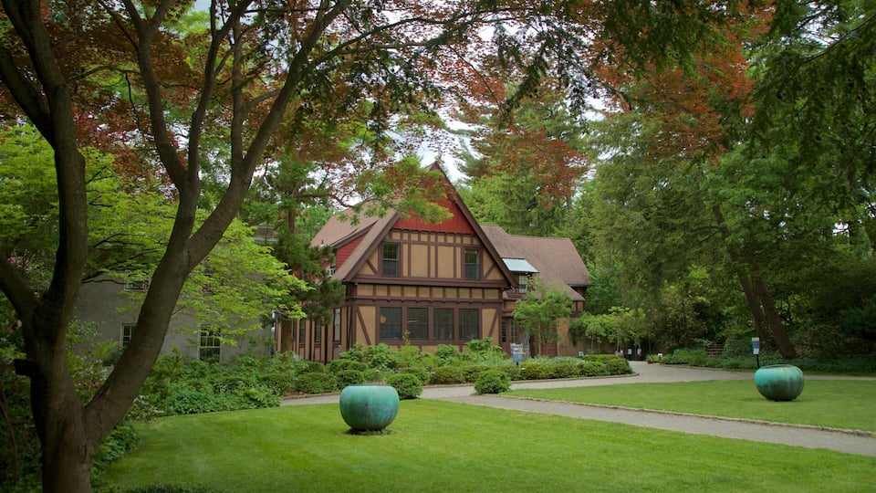 A Tudor-style house surrounded by lush greenery and autumn-colored trees.