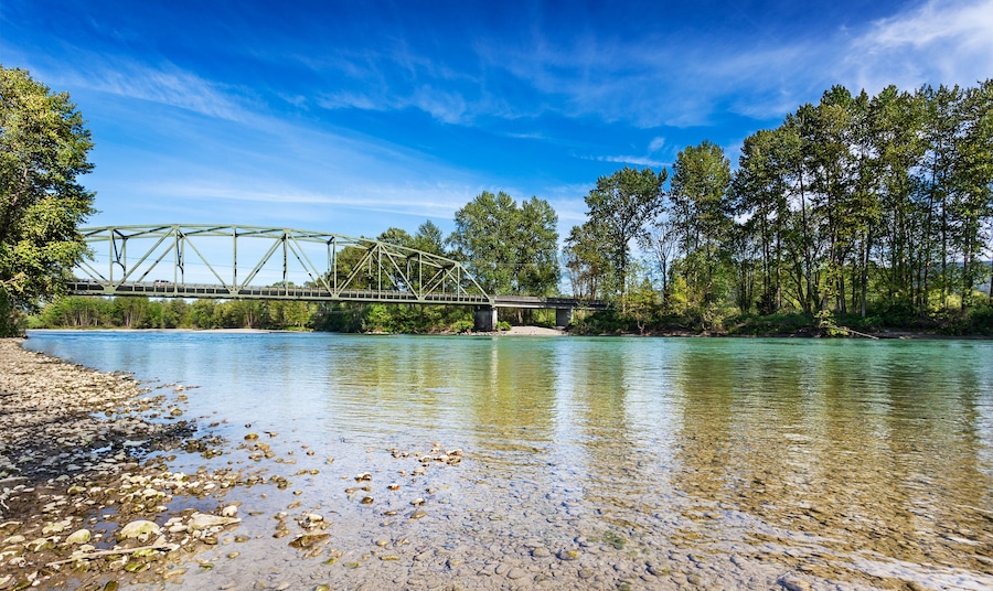 Calm Spring afternoon on the Skykomish River in Monroe, Washington by the Lewis Street bridge. The through truss bridge is state highway 203; Shutterstock ID 411400924