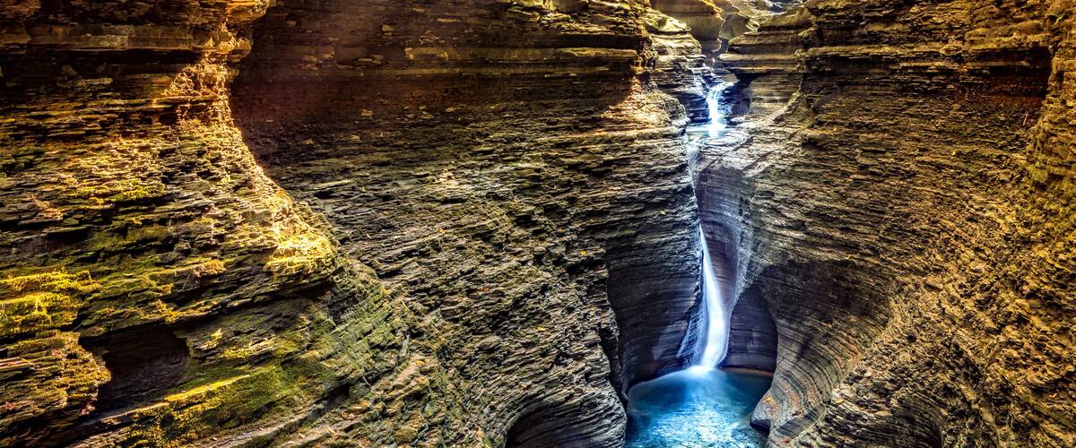 A canyon with a waterfall and a river.