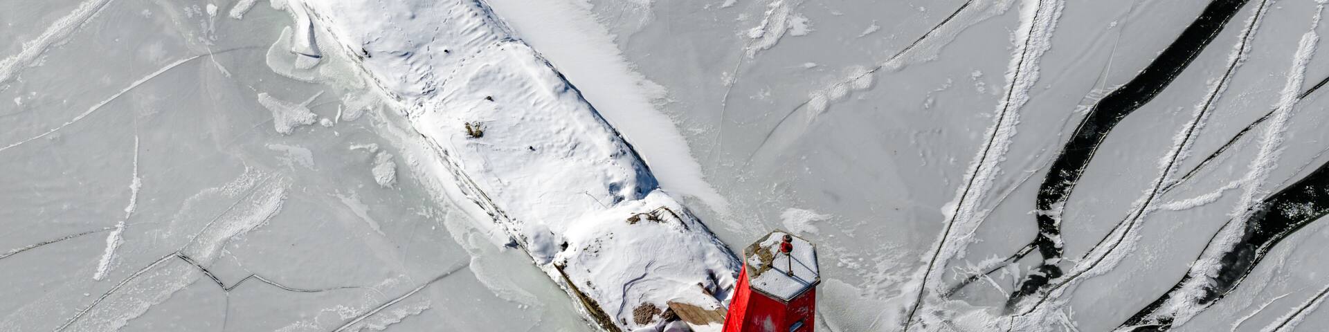 Ithaca, NY, USA - January 30, 2026 Winter aerial photo of the Cayuga Lake Inlet red lighthouse, beacon, with frozen water in Ithaca, NY on a sunny day with snow on the ground.
