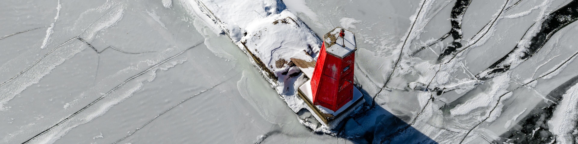 Ithaca, NY, USA - January 30, 2026 Winter aerial photo of the Cayuga Lake Inlet red lighthouse, beacon, with frozen water in Ithaca, NY on a sunny day with snow on the ground.