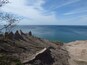A coastal landscape with rocky terrain and a clear view of the ocean.