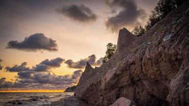 A rocky coastline with a sunset and clouds.