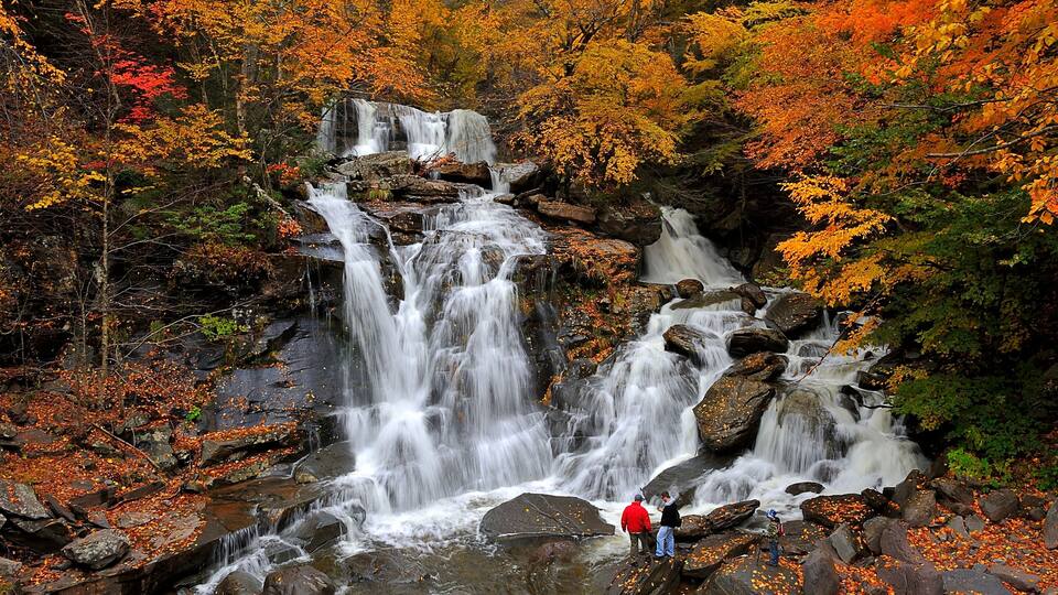 A multi-tiered waterfall surrounded by autumn foliage.