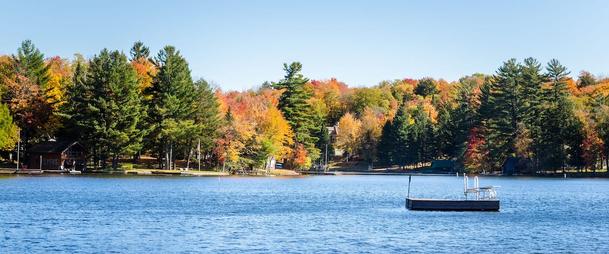 Mountain Lake with Forested Shores in Autumn. A Floating Platform with a Diving Board is in the Middle of the Lake