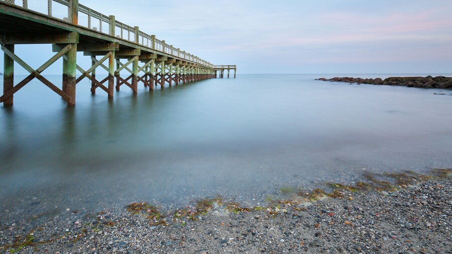 Overview of beautiful fishing pier after sunset at low tide at Walnut Beach, Milford Connecticut, USA.