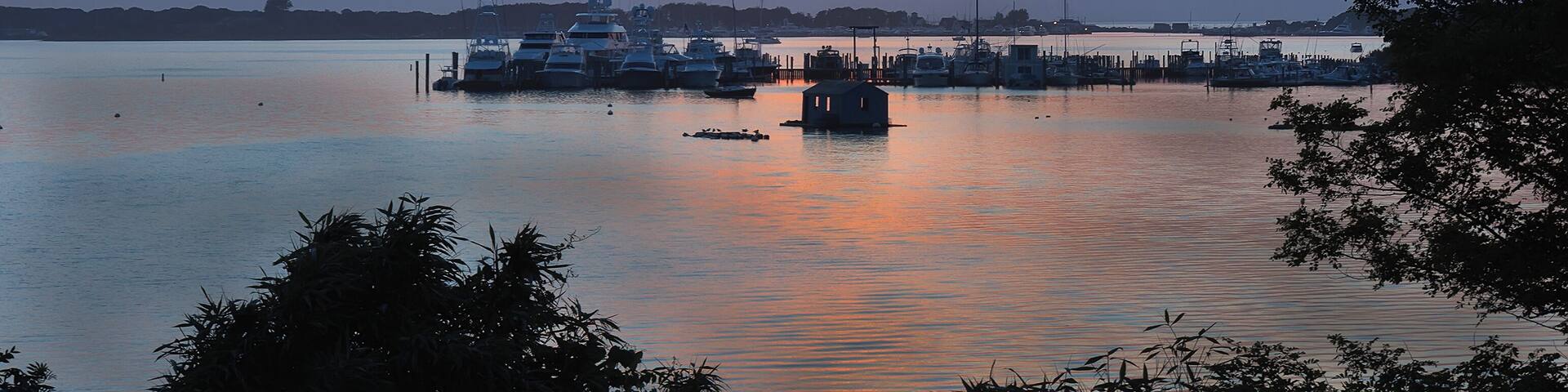 Landscape with lake, boats and sunset sky at Lake Montauk, New York, USA