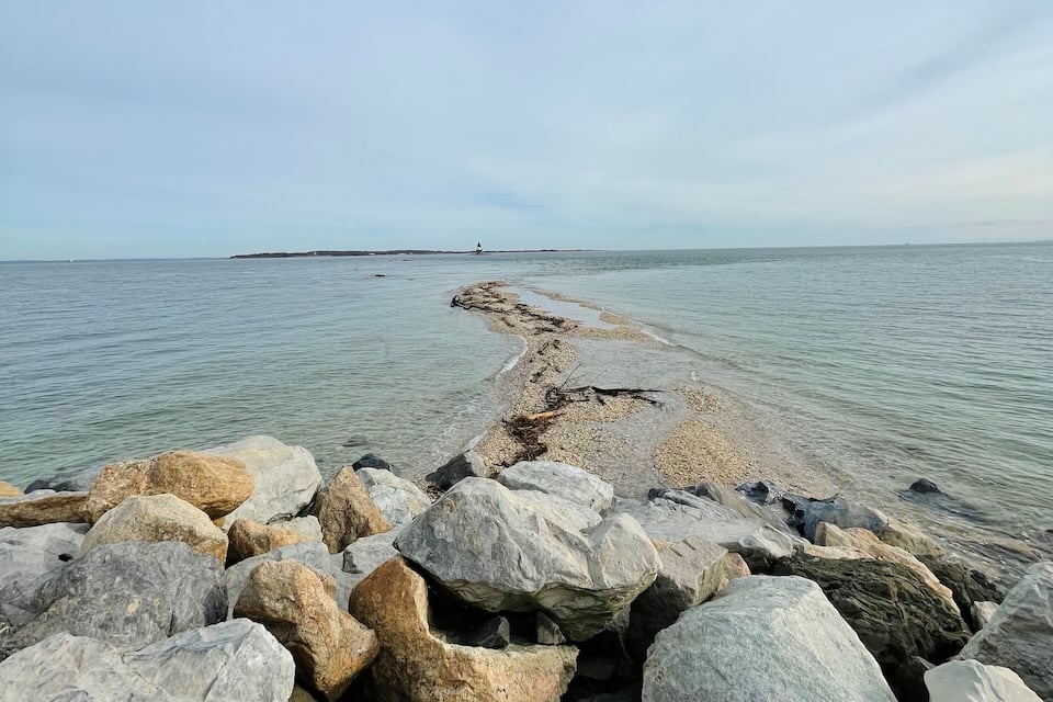 A rocky shoreline with large boulders and a calm sea.