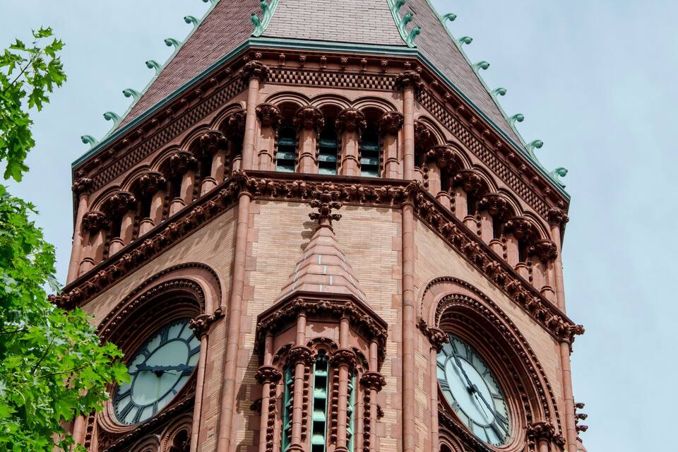 A tall brick tower with a pointed roof and a clock.