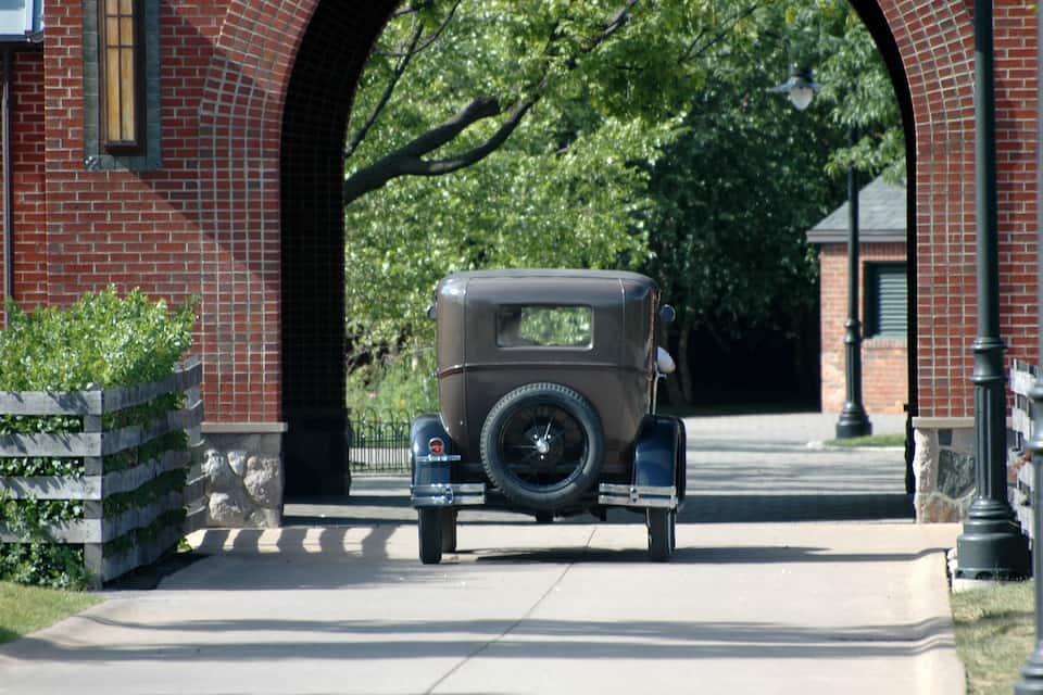 A vintage car parked under a brick archway.