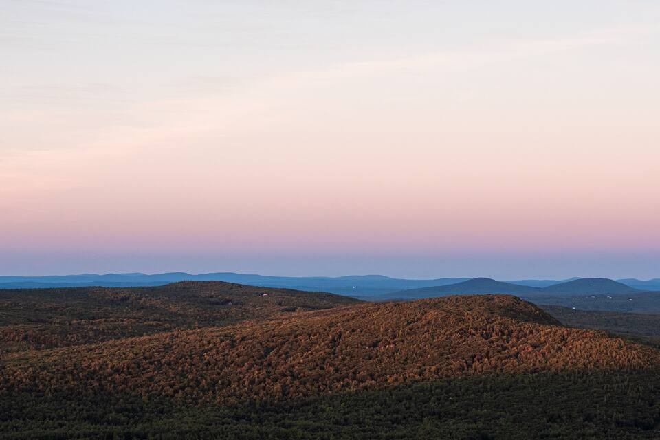 A mountainous landscape with dense forests and rolling hills under a clear sky.
