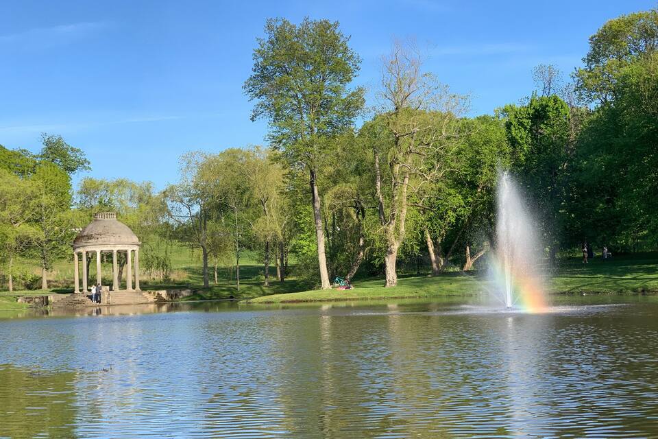 A gazebo, a fountain, and a pond in a park.