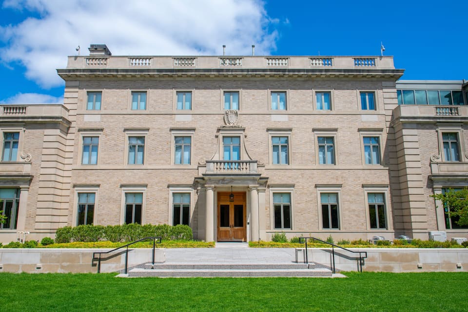 A large, historic building with a symmetrical facade, large windows, and a central entrance with a decorative pediment.