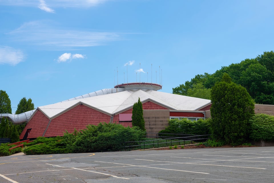 A red barn with a white roof and a cylindrical structure on top.