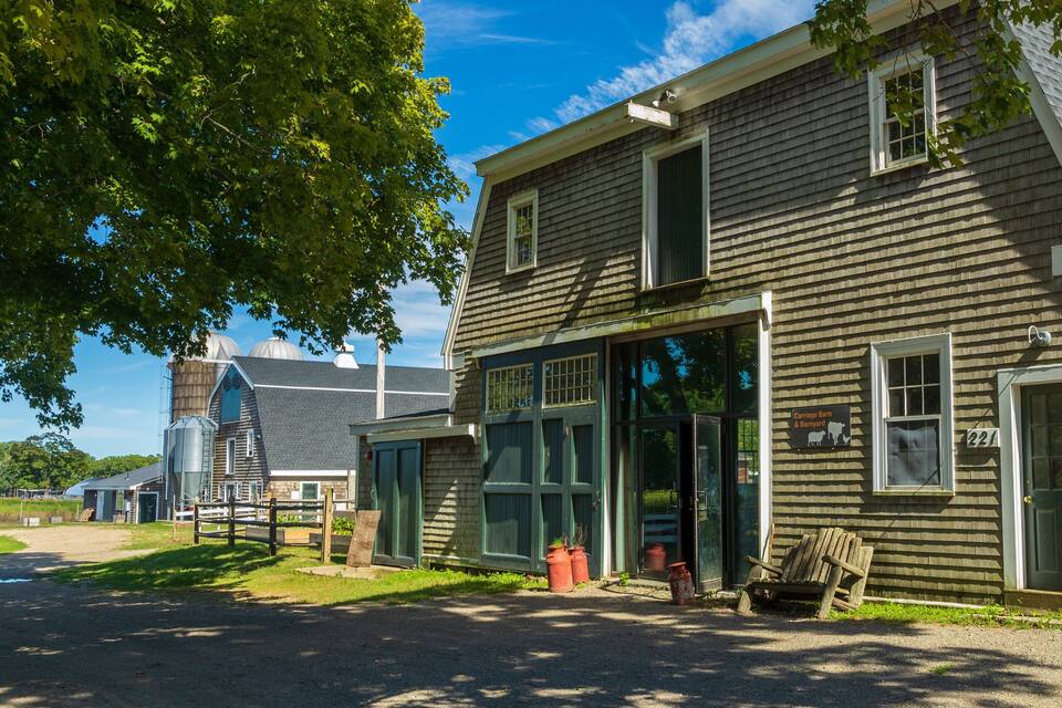 A historic building with large windows and a sign reading "Carriage Barn & Barnyard".