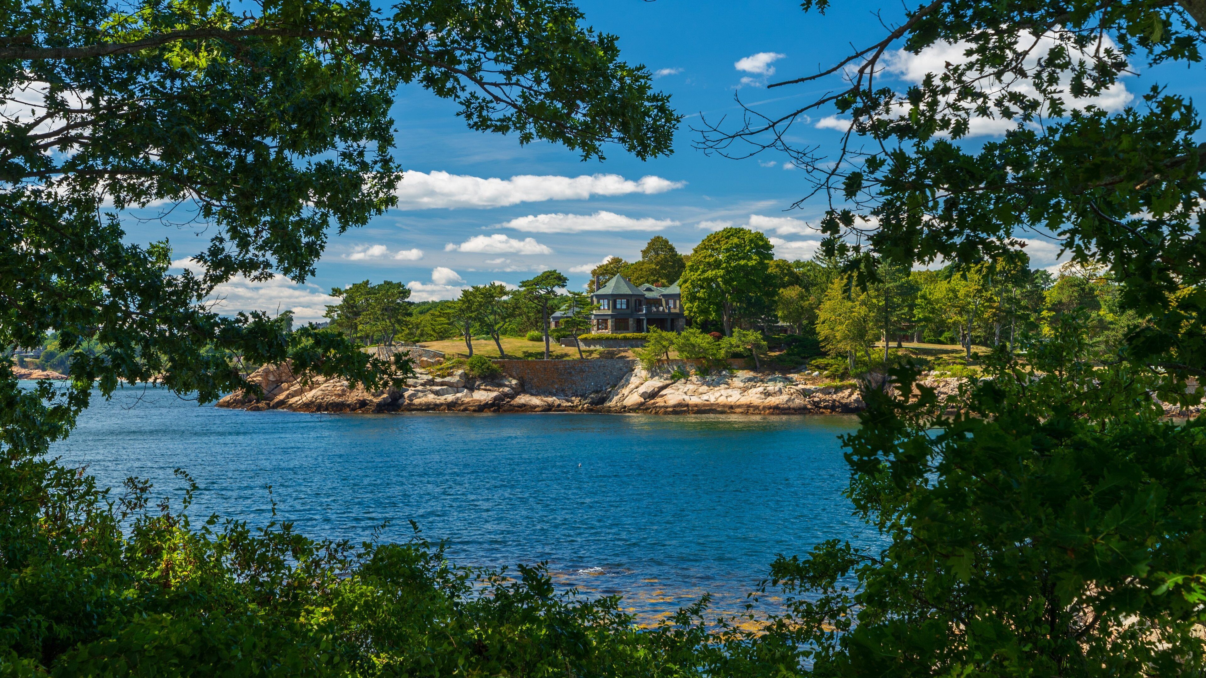 Une maison au bord du lac, entourée d’arbres et bordée d’une côte rocheuse.