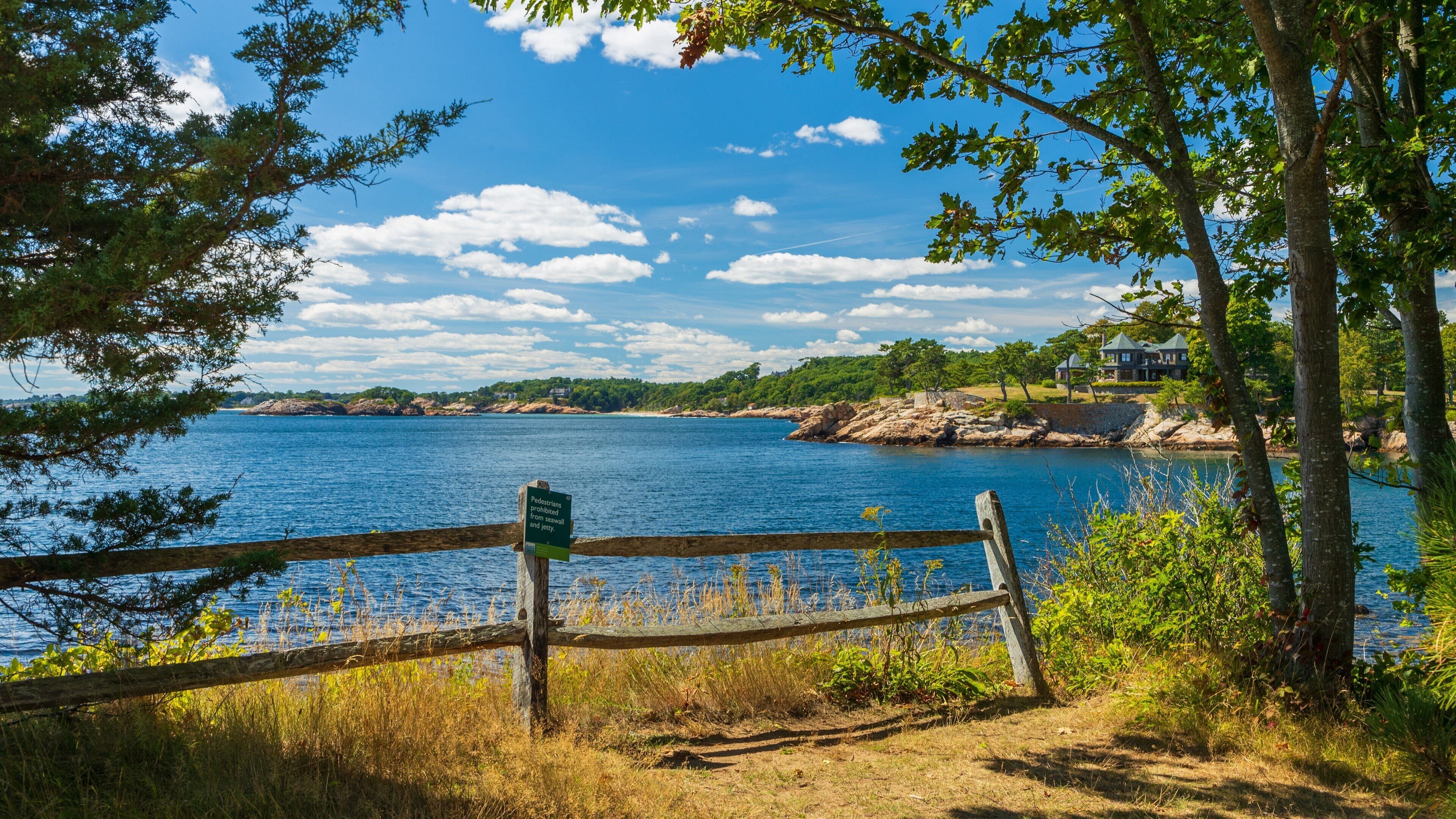 A wooden fence with a sign prohibiting pedestrians from the shoreline.