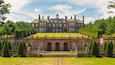 A large stately building with a green lawn, a central dome, and a symmetrical facade.