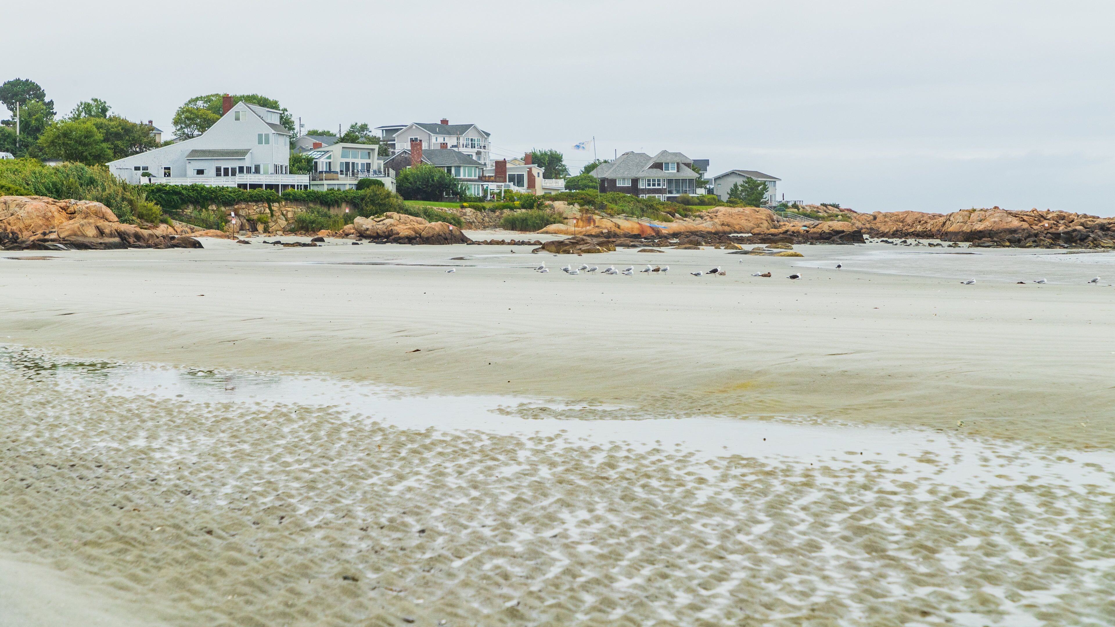 Une plage de sable avec une rangée de maisons en arrière-plan.