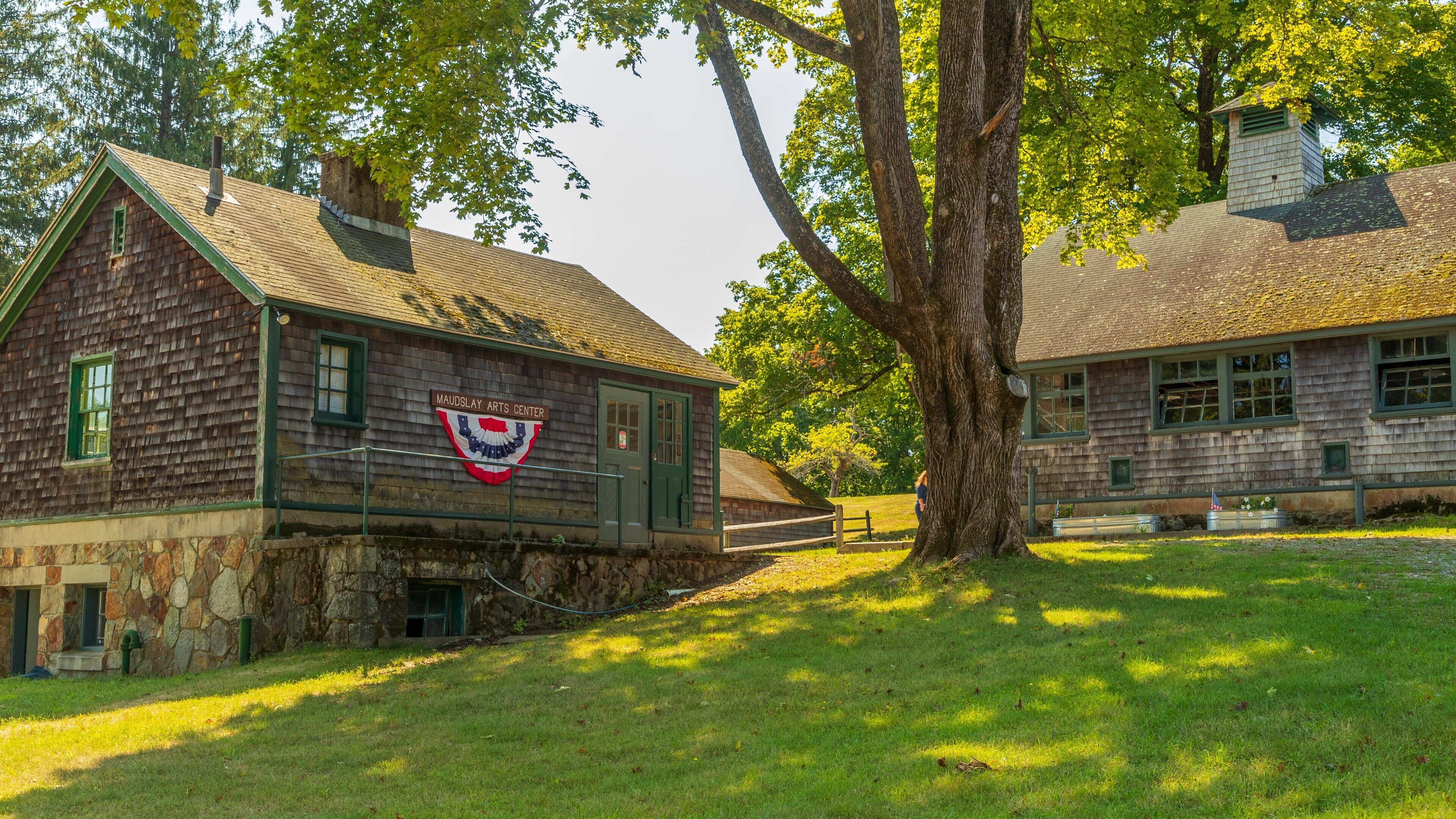 A historic building with a green roof and a flag, surrounded by trees and grass.