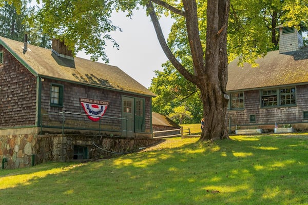 A historic building with a green roof and a flag, surrounded by trees and grass.