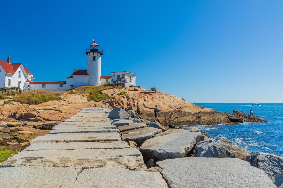 Un faro en una costa rocosa bajo un cielo azul despejado.