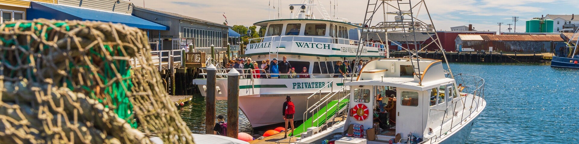 Un puerto con barcos, incluyendo un barco llamado 'Whale Watch' y otro llamado 'Wejack'.
