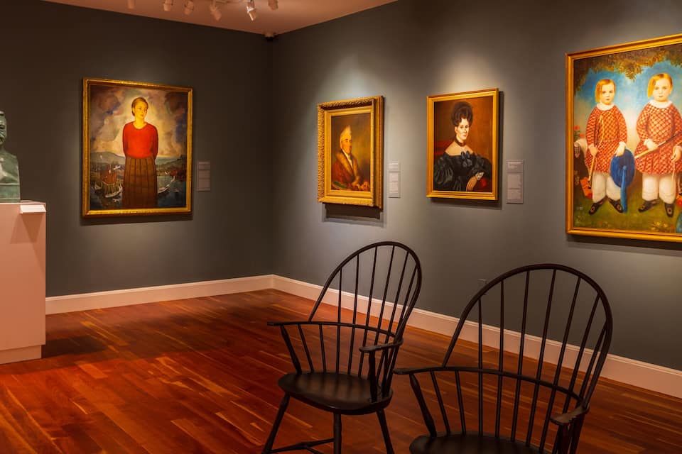 Una galería de arte con suelo de madera y pinturas en las paredes.