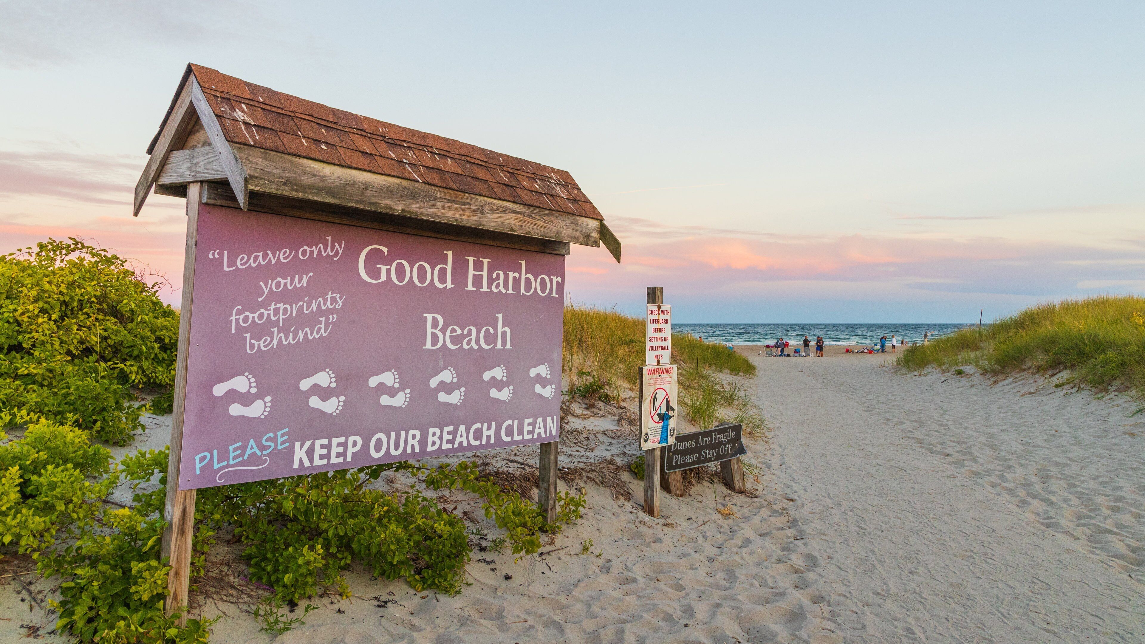 A beach sign with footprints and a message to keep the beach clean.