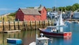 A harbor with a red barn, boats, and houses along the shore.
