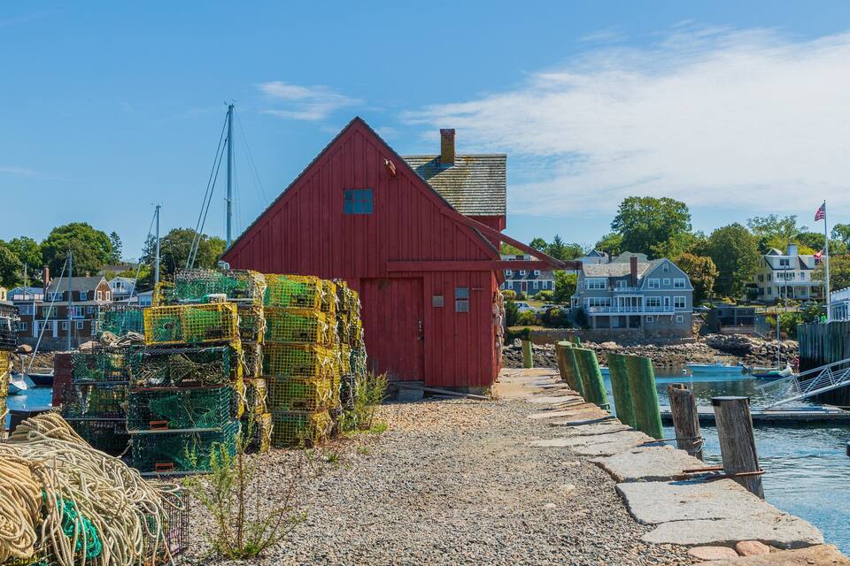 En rød bygning, en bro og huse langs en havnefront.