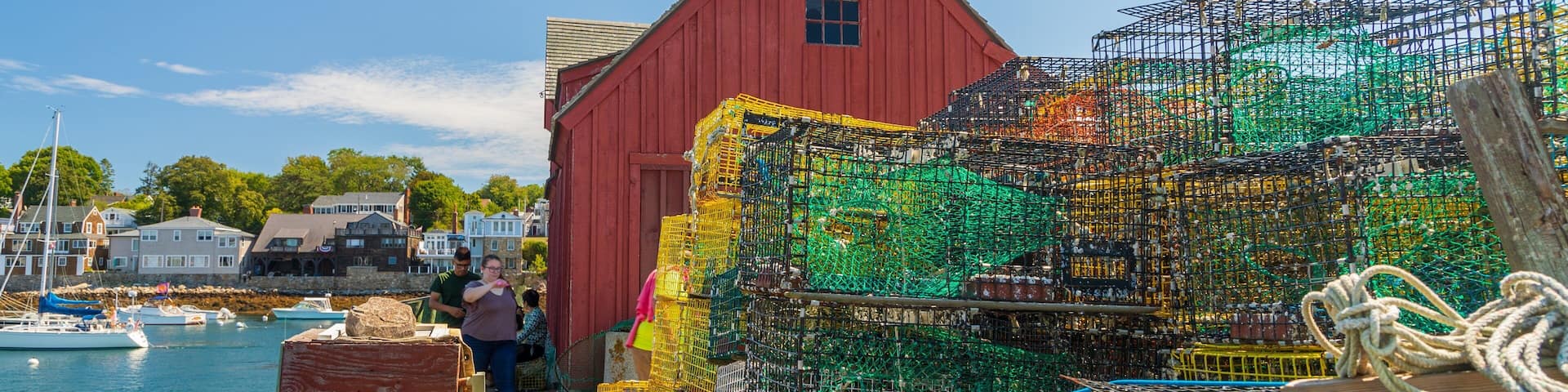 A red building by a harbor with stacked lobster traps.