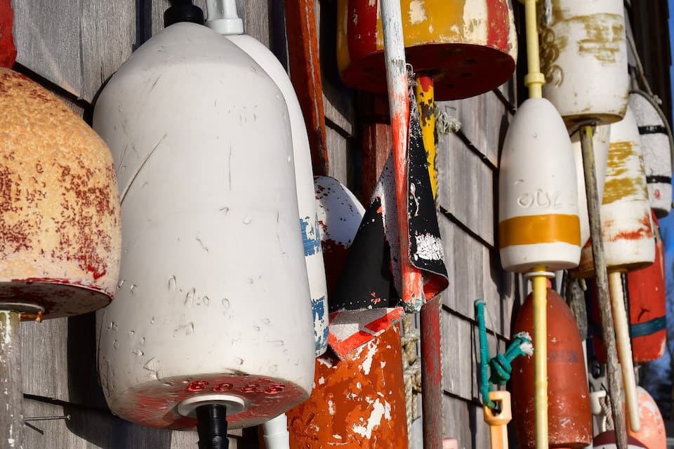 A collection of colorful buoys and markers against a wooden wall.