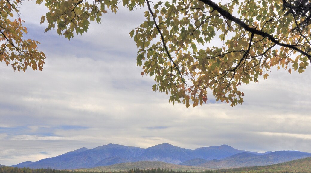 Peaceful autumn scene in New Hampshire’s White Mountains. Late afternoon with distant mountains reflected on calm surface of Cherry Pond near rural Jefferson.