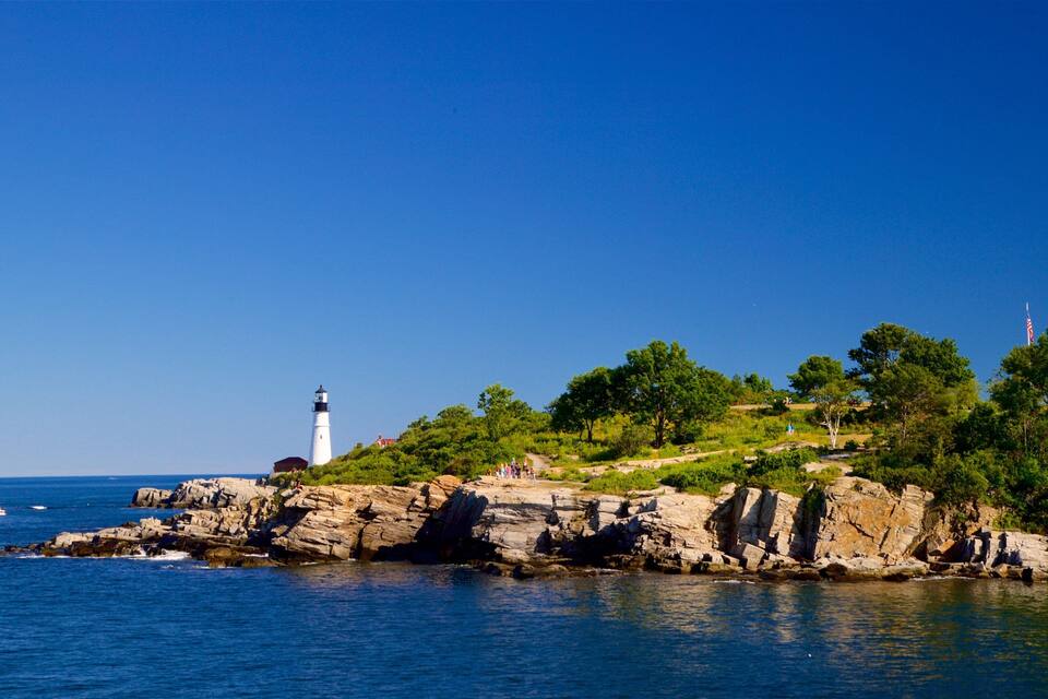 Un faro sobre una costa rocosa con cielos azules despejados.