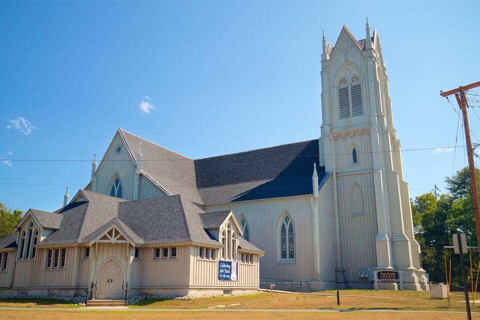 A church with a tall steeple and a smaller building with a sign celebrating 300 years.