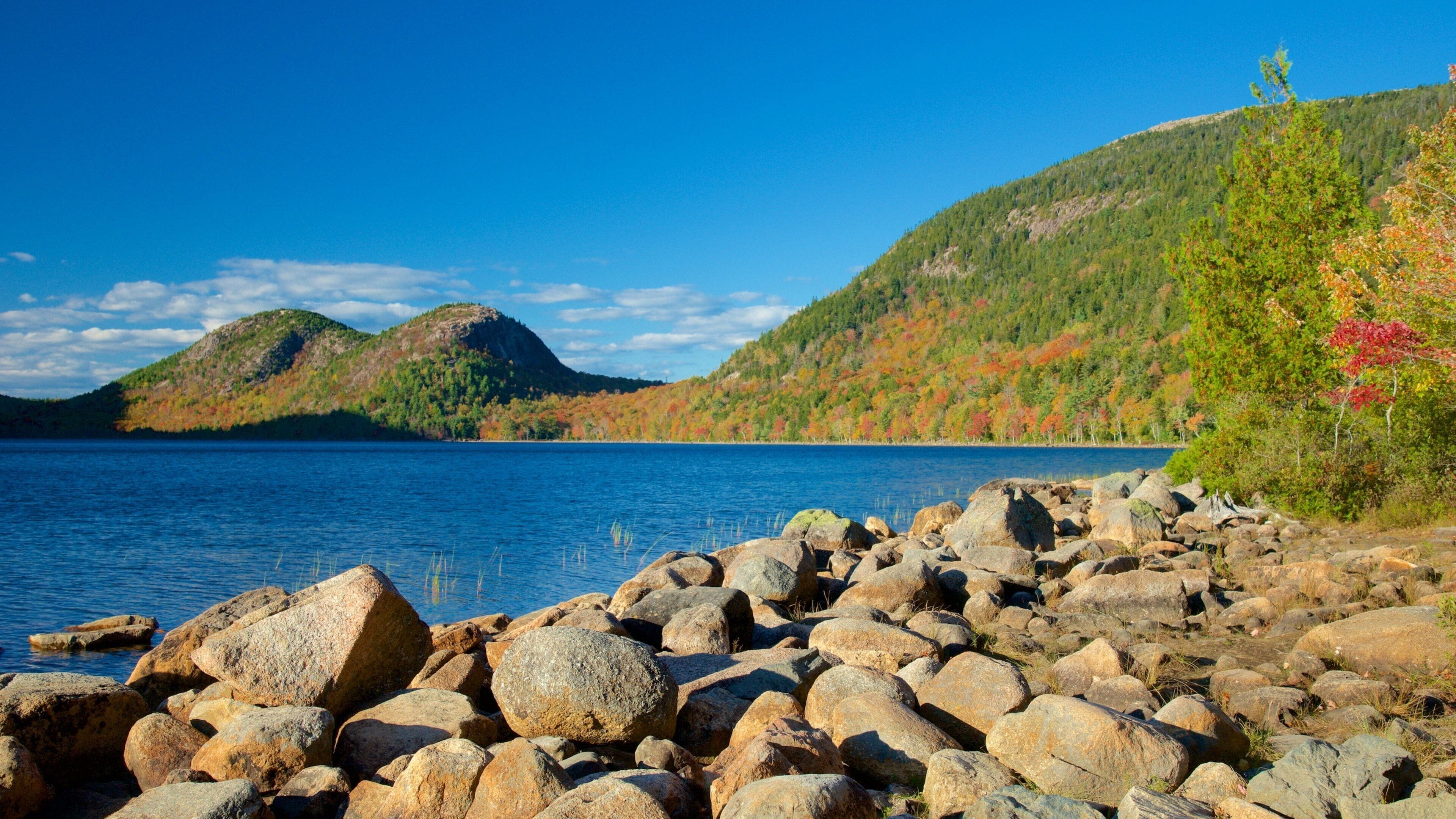 A rocky shoreline with a lake and hills in the background.