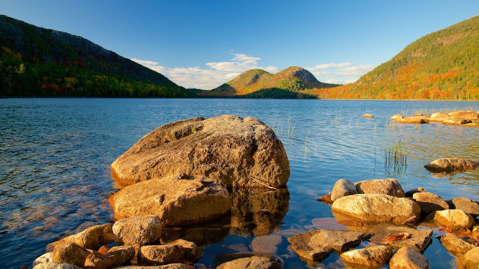 A lake with large rocks in the foreground and mountains in the background.