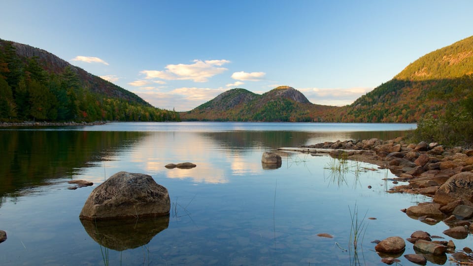 A calm lake surrounded by mountains with autumn foliage.