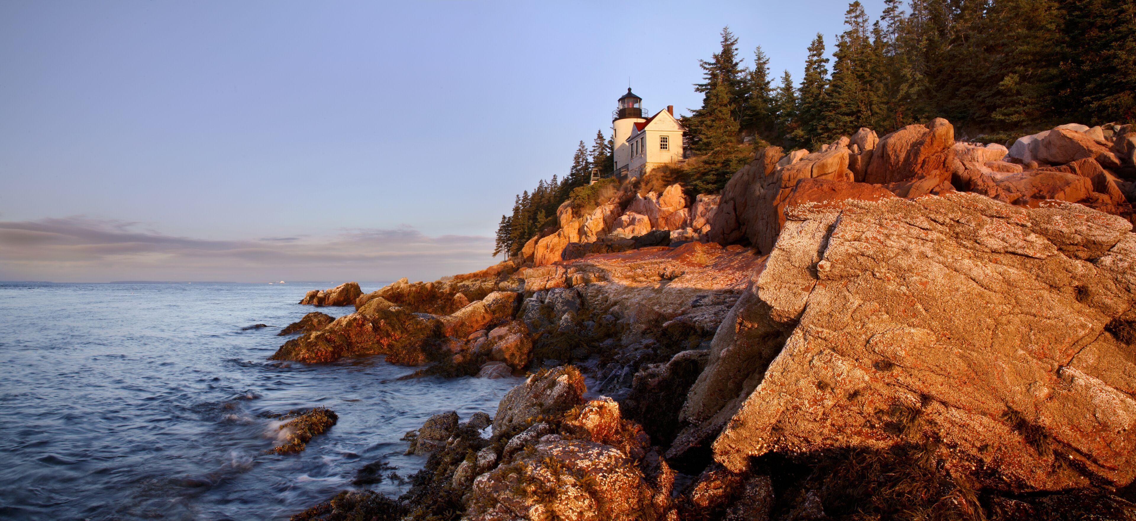 A coastal lighthouse on a rocky outcrop with ocean waves.
