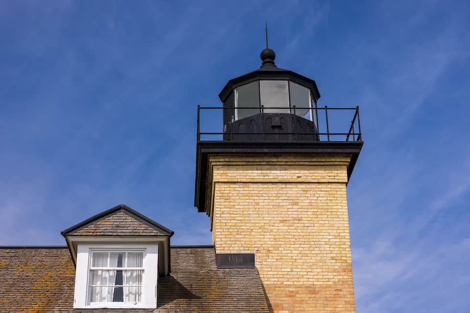 A lighthouse with a brick tower and a white window.