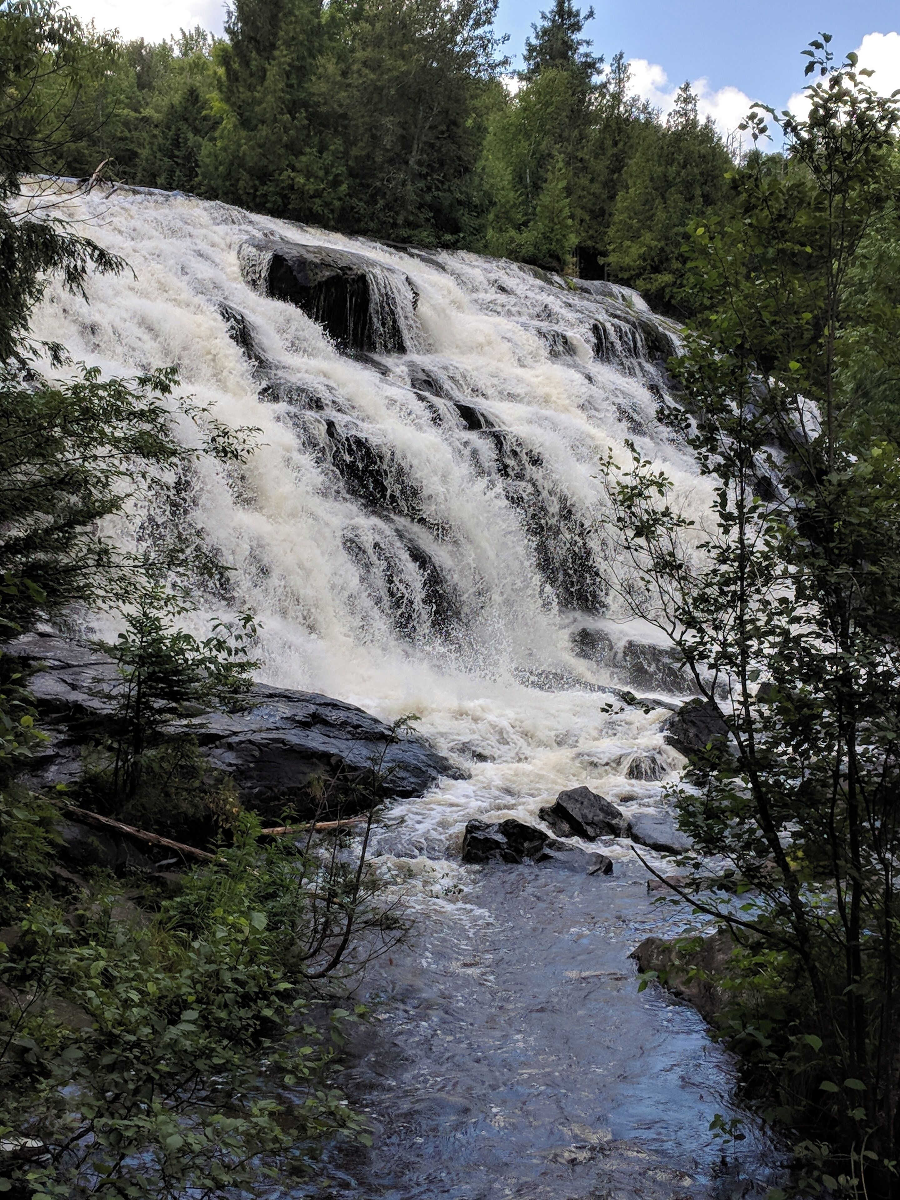 A waterfall cascading over rocks in a forested area.