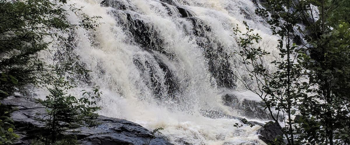 A waterfall cascading over rocks in a forested area.