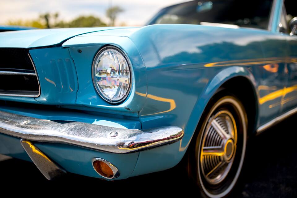 Un coche azul clásico con detalles cromados y franjas amarillas.