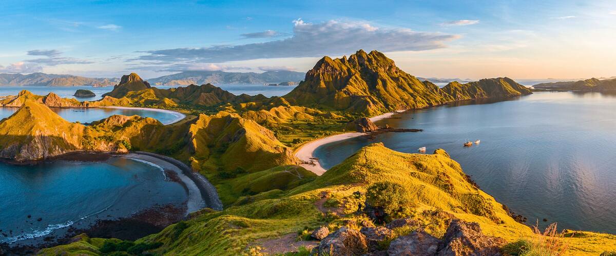 A coastal landscape with green hills, a curved bay, and several small islands.